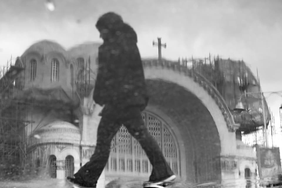 A figure strides past a church arch, photographed by Medhat Soody